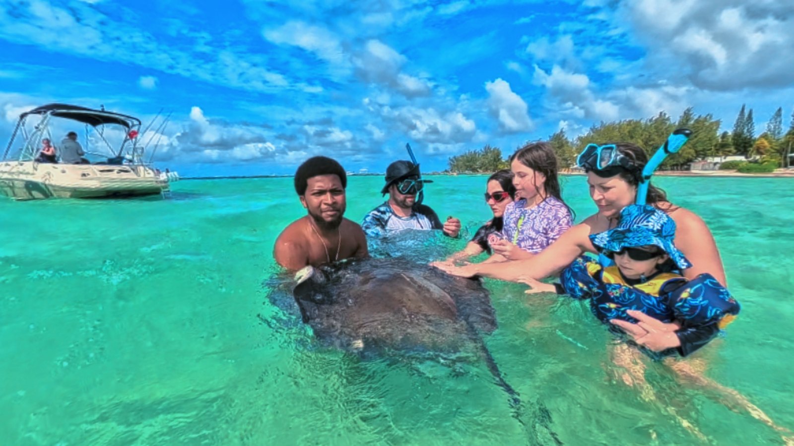 Family smiling together on a private boat excursion in Grand Cayman with Cayman Kind Watersports.